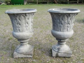 A pair of composition stone trumpet shaped garden urns, with moulded acanthus detail, raised on