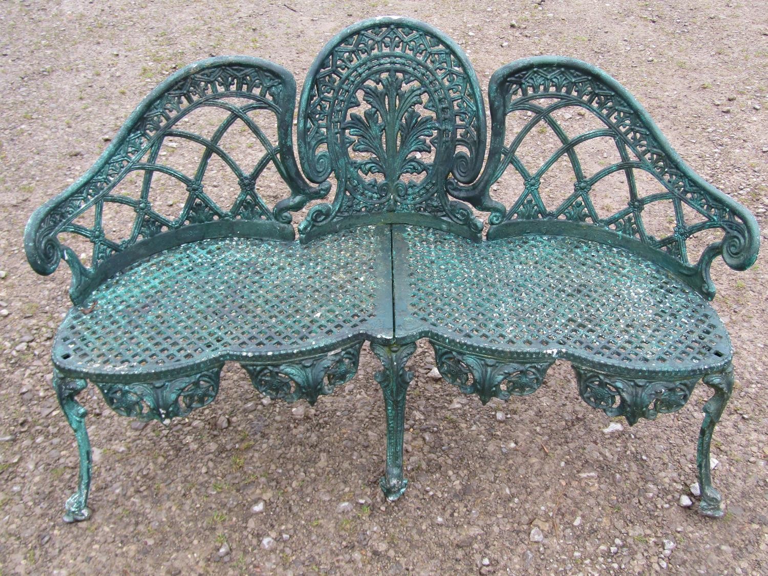 A weathered green painted cast alloy garden bench with shaped outline and decorative pierced