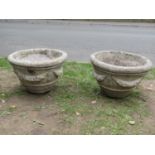 A pair of weathered cast composition stone garden planters of circular tapered form with fruiting