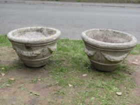 A pair of weathered cast composition stone garden planters of circular tapered form with fruiting