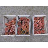 Three weathered wooden crates containing a quantity of terracotta flower pots of varying size and