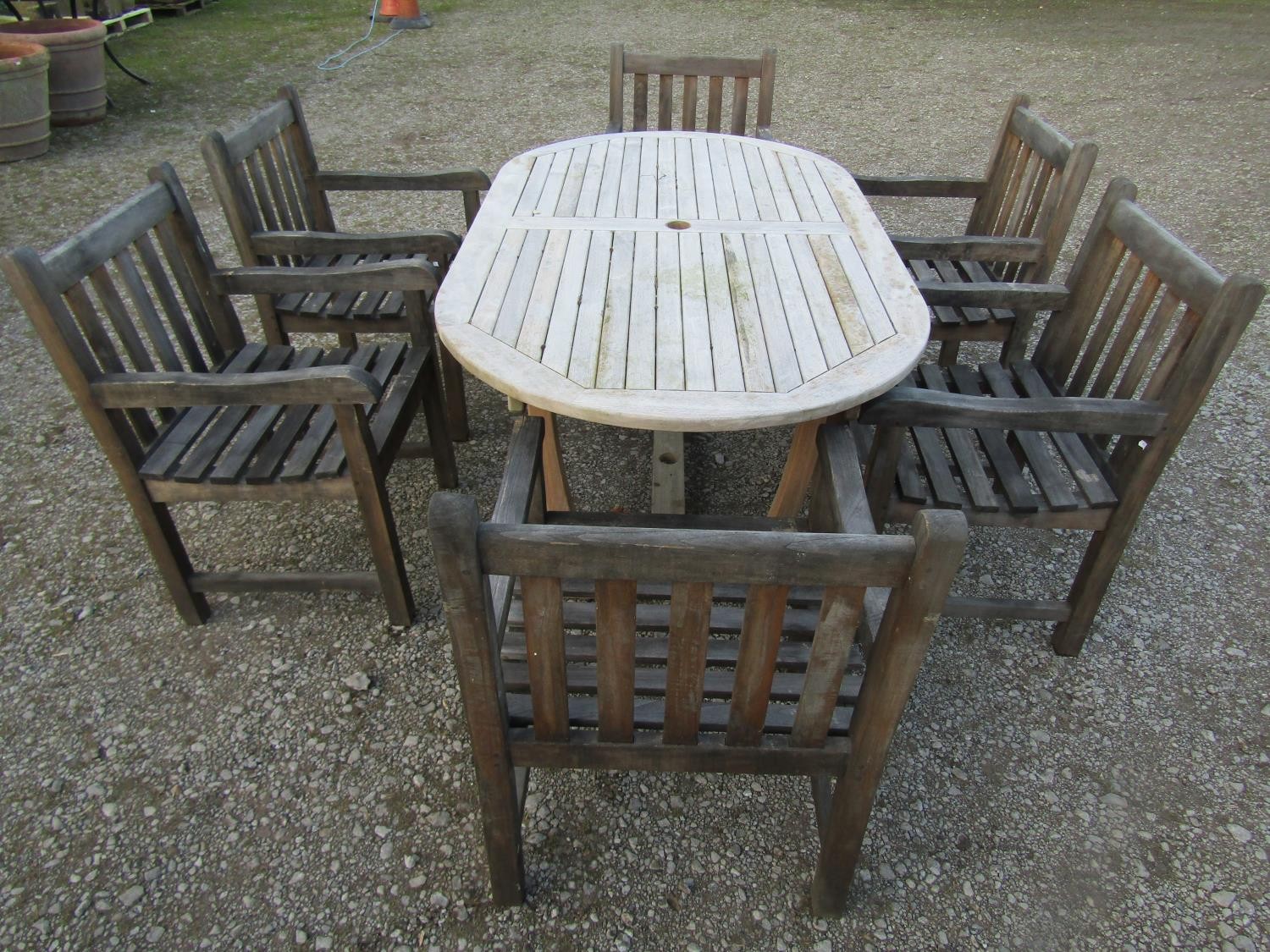A contemporary Cotswold Collection weathered teak garden table with oval slatted top raised on