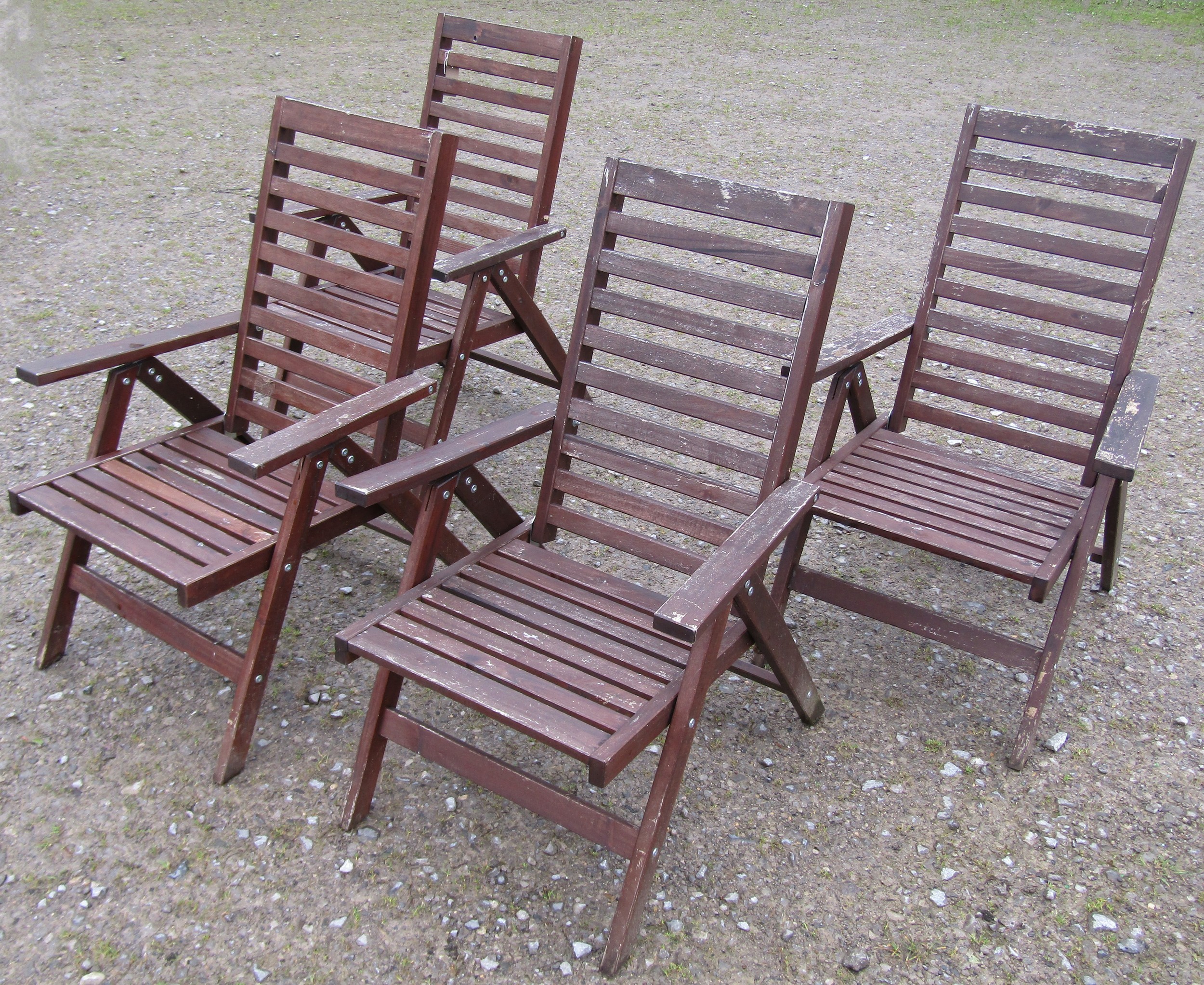 A set of four stained and weathered contemporary folding hardwood garden armchairs with slatted