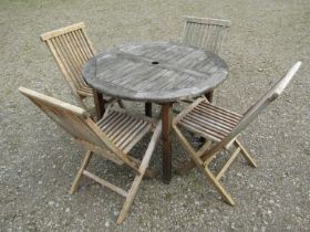 A small weathered teak garden table with circular slatted top, raised on square cut supports,
