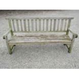 A well weathered teak garden bench with slatted seat and back and open scrolled arms, 198 cm long (