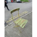 A small rustic painted iron-framed folding patio chair, with green-painted finish