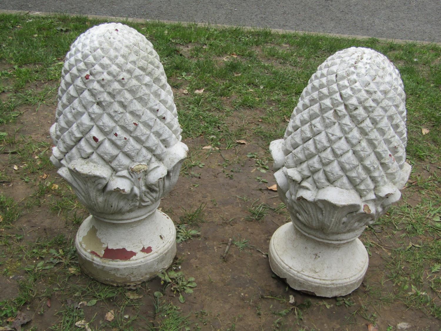 A pair of painted and weathered cast composition stone pier caps in the form of pineapples