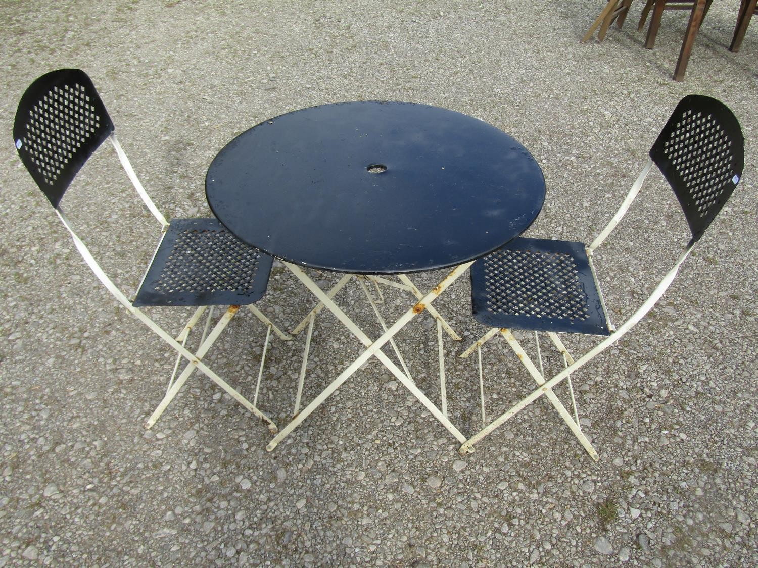 A painted folding steel three piece Bistro set with lattice detail, the table 77cm diameter (af)