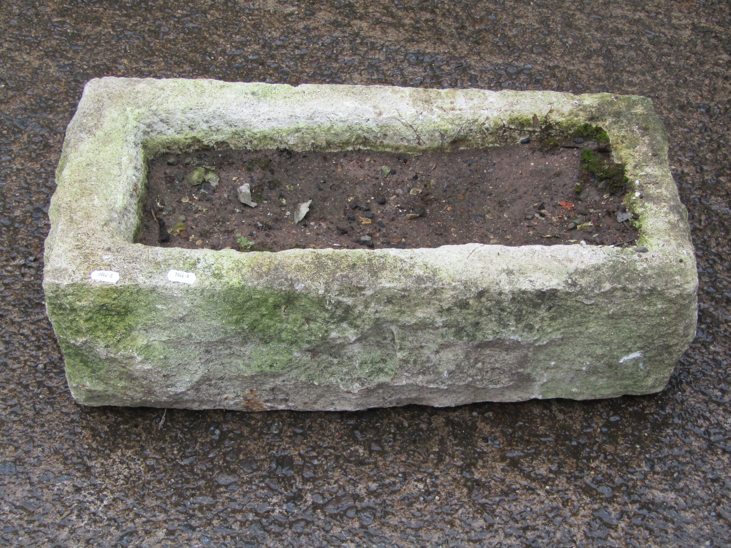 A weathered rough hewn rectangular natural stone trough 20 cm high x 64 cm long x 33 cm wide