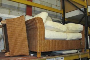 A Wicker two seat conservatory sofa with swept arms and loose seat cushions together with a matching