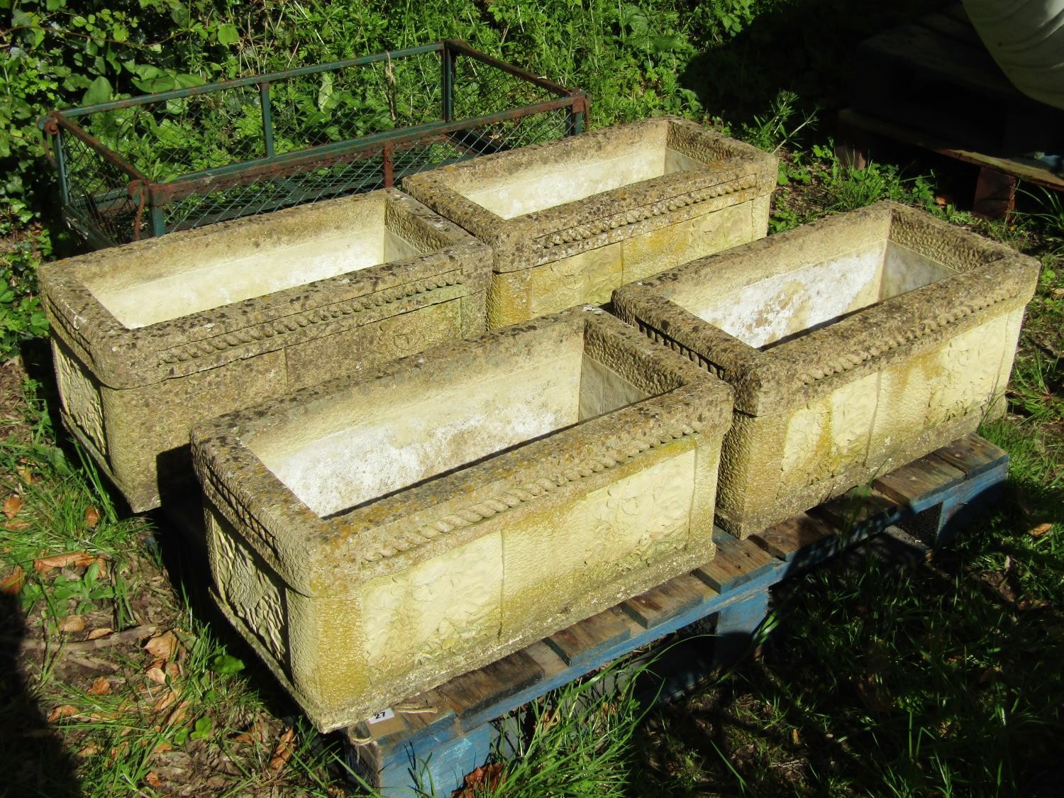 A set of four weathered composition stone garden troughs of rectangular form with repeating owl,