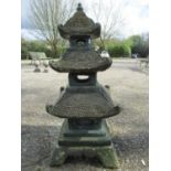 A weathered green painted cast composition stone sectional garden pagoda ornament, 105 cm high