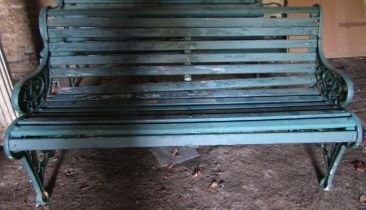 An old garden bench with painted wooden slatted seat and combined back raised on decorative cast