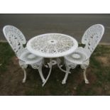 A cream painted cast aluminium garden table of circular form with decorative pierced scrolling