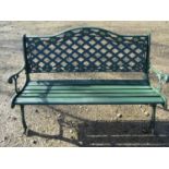 A green painted garden bench with wooden slatted seat beneath a cast iron pierced lattice panelled