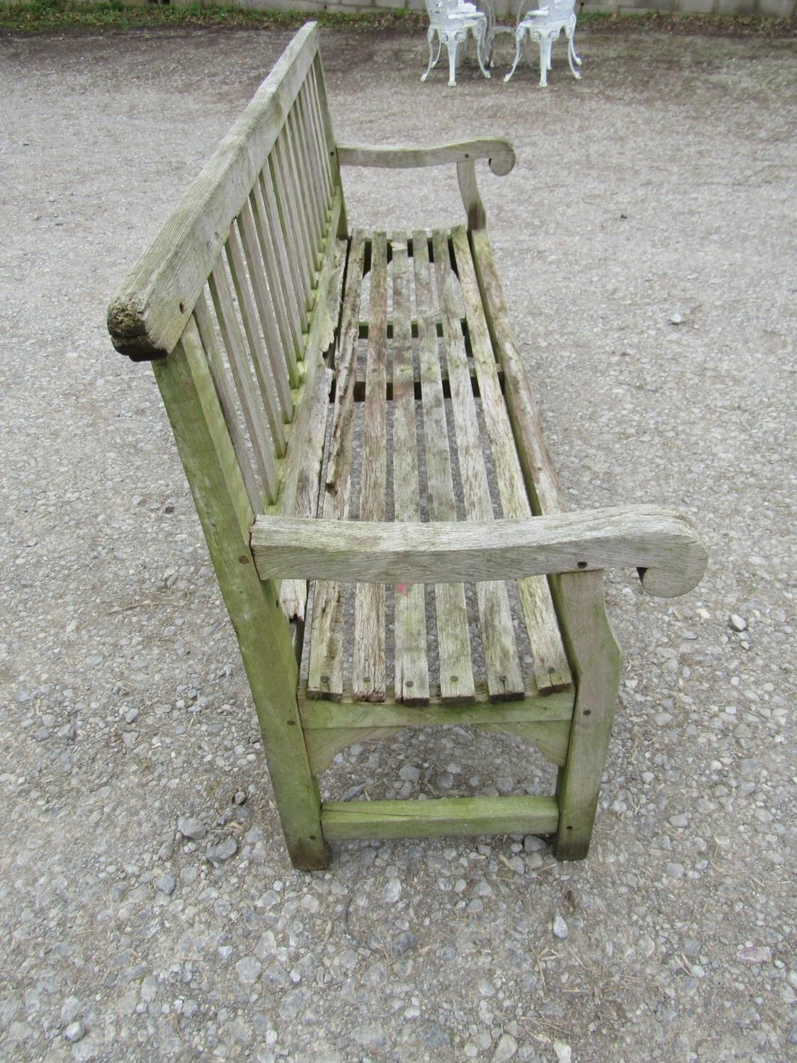 A well weathered teak garden bench with slatted seat and back and open scrolled arms, 198 cm long ( - Image 4 of 7