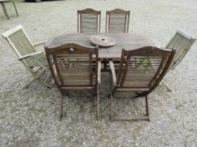 An associated weathered contemporary teak garden suite comprising table with oval slatted panelled
