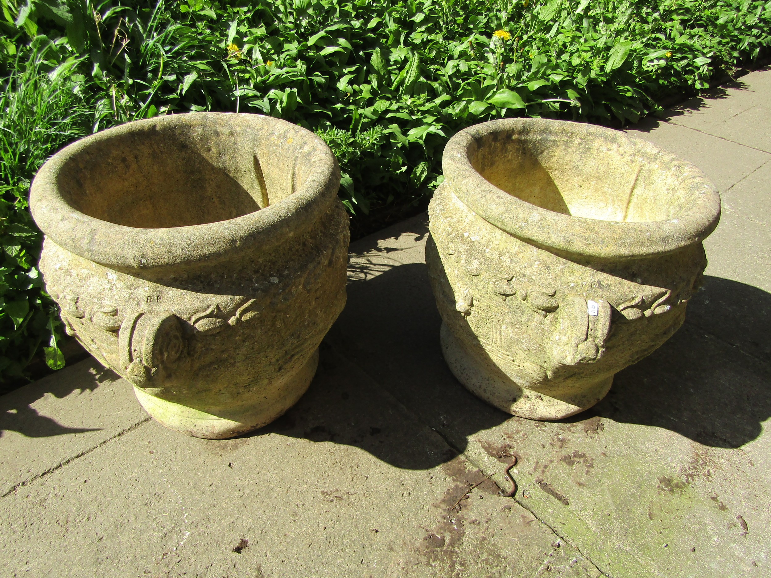 A pair of weathered cast composition stone roman type urns, the circular bowls with fixed scrolled - Image 2 of 3