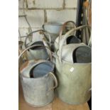 Five vintage galvanised watering cans of varying design and capacity together with a bucket and a