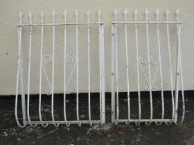Two cream painted steel balcony rails with simple open scroll work detail and spear head finials,