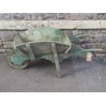 A small traditional wheelbarrow with weathered green painted finish