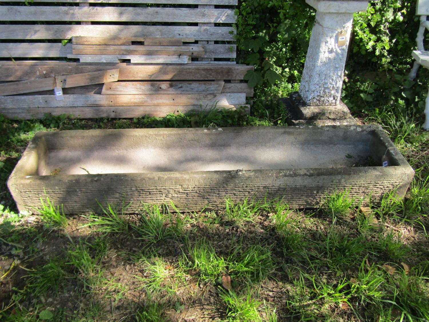 A weathered carved natural stone trough of rectangular form with slightly dished interior and