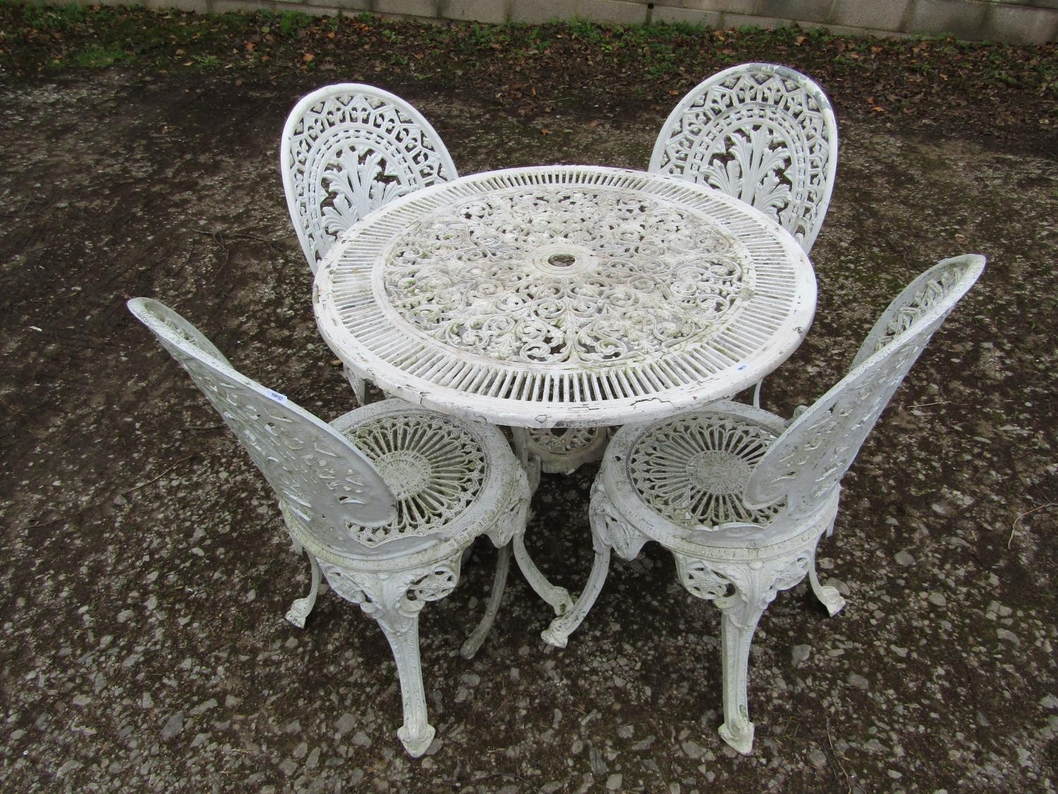 A weathered cream painted cast aluminium garden terrace table with decorative pierced circular top