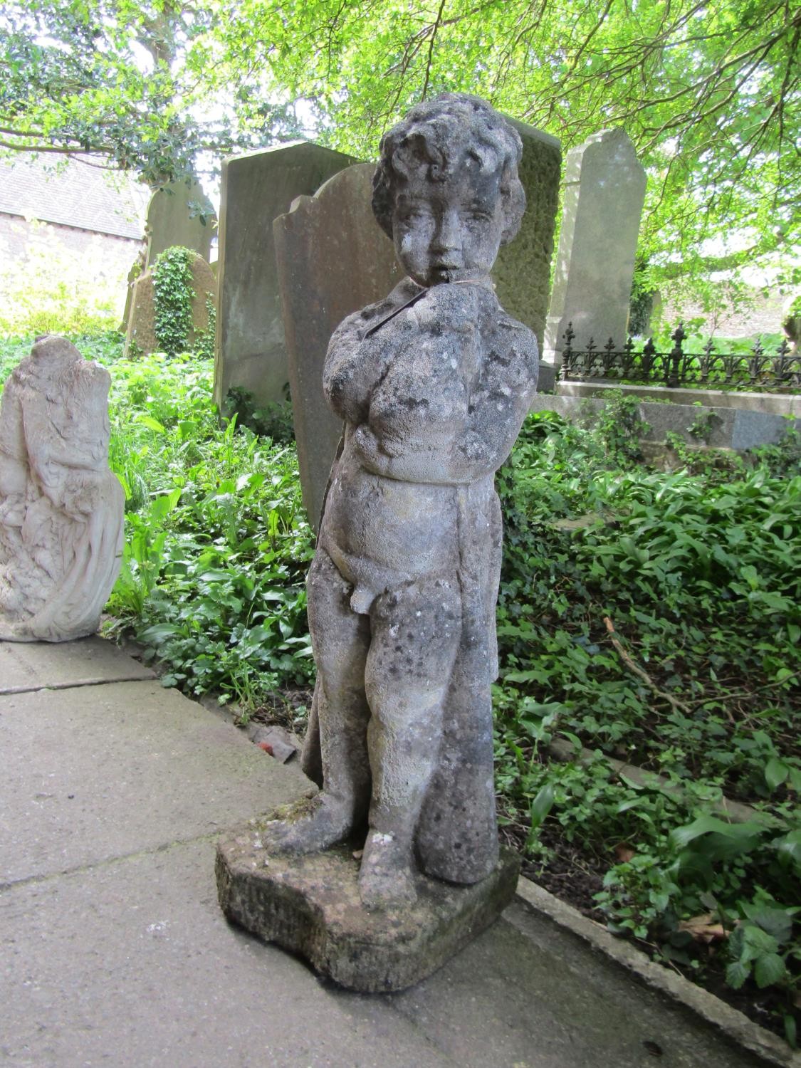 A weathered cast composition stone garden ornament in the form of a boy wearing a long trench coat - Image 2 of 4