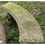 A weathered three-sectional cast composition stone garden bench, the curved slab seat with tongue