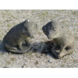 A large decorative pair of weathered cast composition stone pigs in seated pose, 44cm high, 45cm