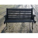 A two seat garden bench with stained wooden slatted seat raised on decorative pierced and scrolled