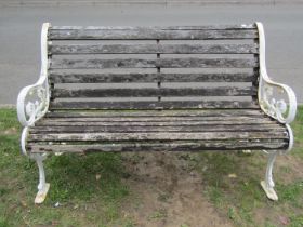 A two seat garden bench with slatted seat and combined back raised on painted cast iron scroll