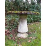 A good quality weathered reconstituted garden table, the circular top raised on a turned and