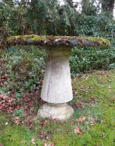 A good quality weathered reconstituted garden table, the circular top raised on a turned and