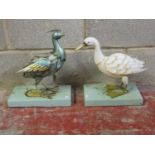 Two novelty painted sheet tin bird ornaments set on green painted wooden platform bases, 40 cm