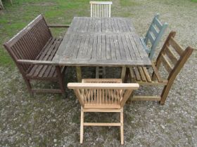 An associated suite of garden furniture comprising a weathered teak table with rectangular slatted