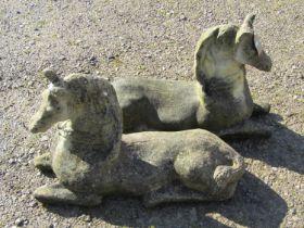 A pair of weathered cast composition stone terrace or pier ornaments in the form of recumbent
