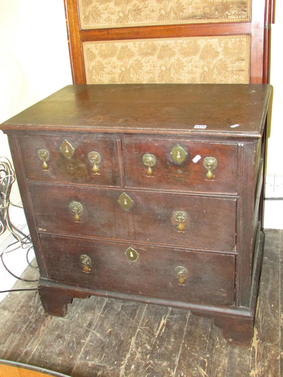 A small 18th century oak chest of two long and two drawers raised on bracket supports with pear drop