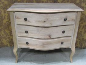 A hard wood serpentine chest of three drawers on shaped supports, 100cm wide
