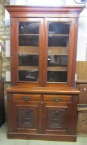 An Edwardian library bookcase in walnut, the base enclosed by a pair carved and panelled doors and