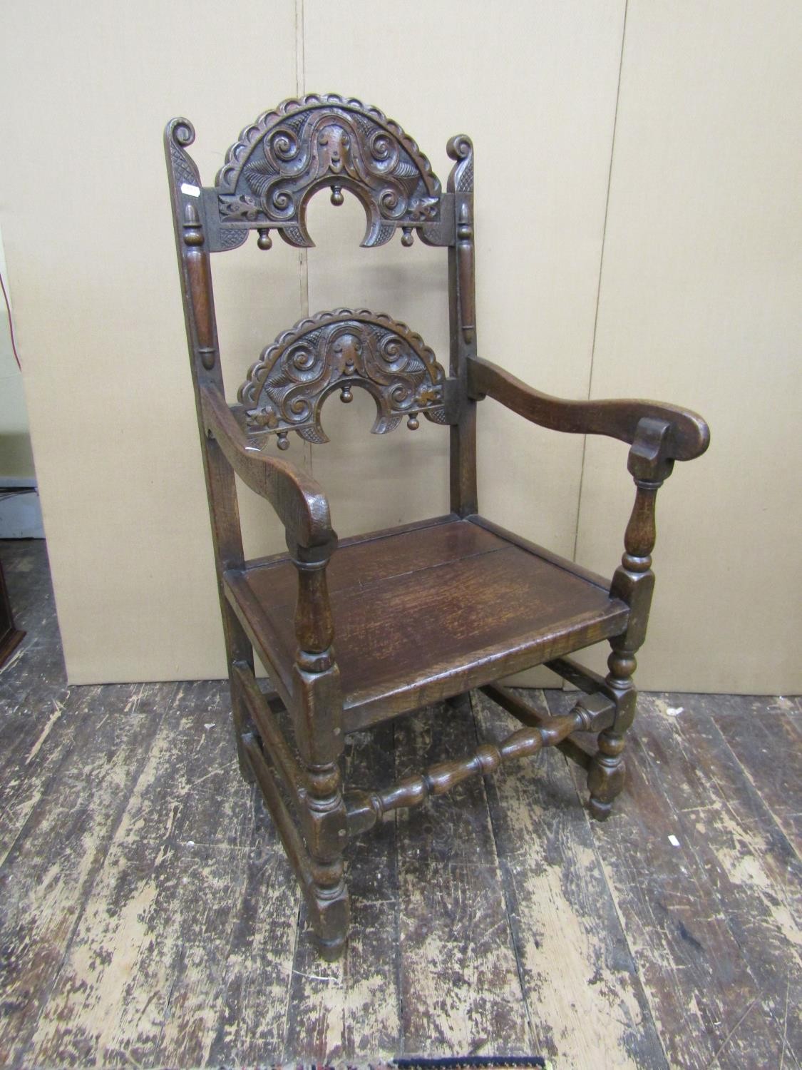 An antique oak South Yorkshire elbow chair of traditional form with carved and arched ladder back,
