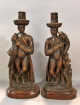 An amusing symmetrical pair of 19th century continental carved folk art type ‘poacher’ candlesticks,