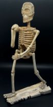 An unusual 19th century folk art / German school bone work figure of a striding skeleton, in one arm