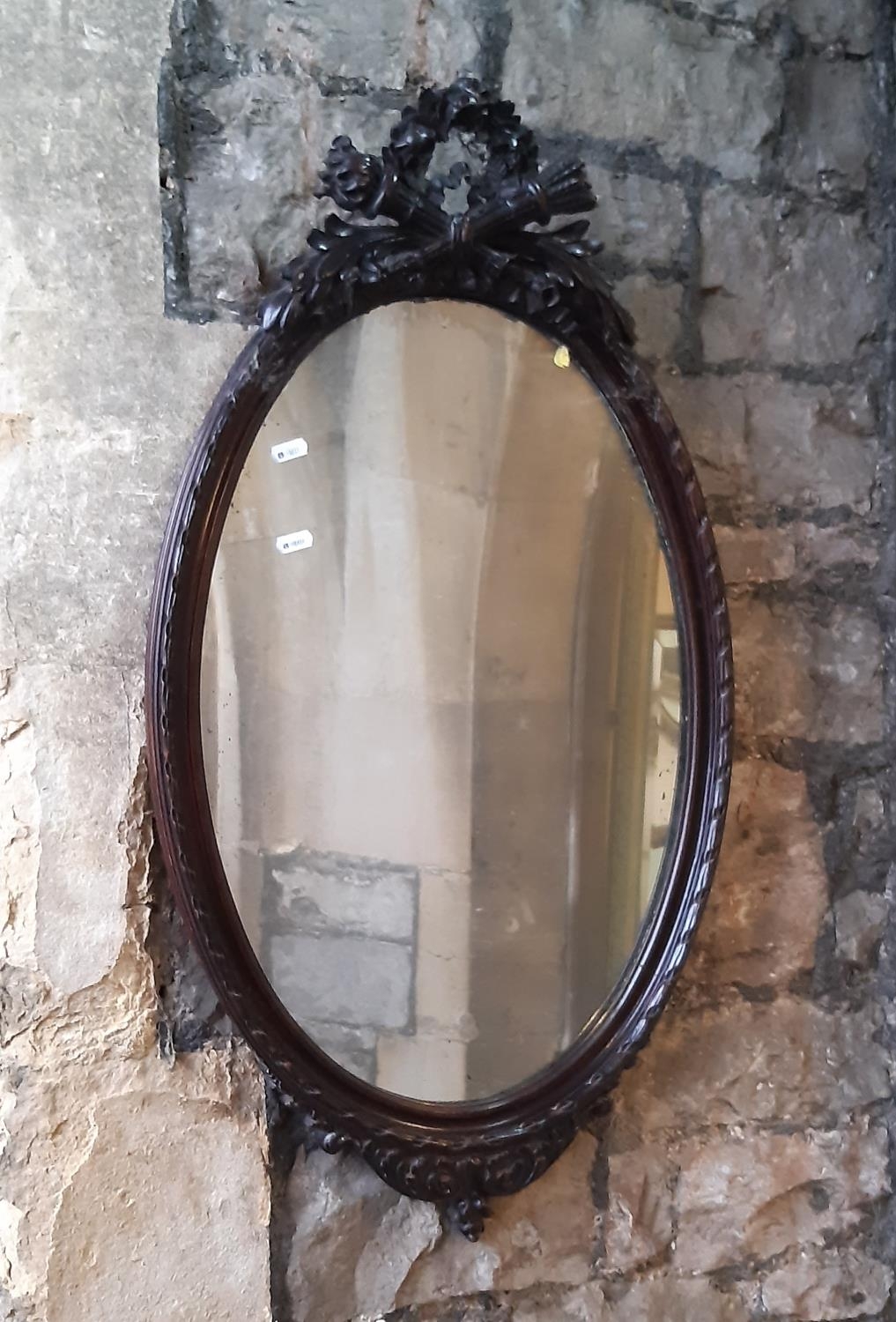 A carved plaster French wall mirror of oval form with pierced and decorated pediment, 90cm max