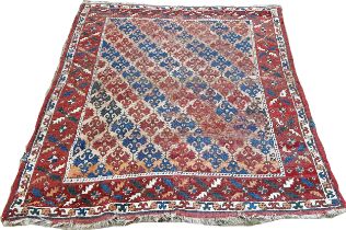 An old Persian rug with diagonal red and blue geometric patterns, worn in places, 163cm x 136cm