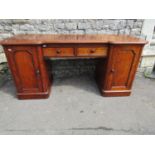 A Victorian mahogany inverted breakfront desk with two central drawers flanked by panelled