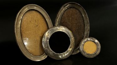 A pair of oval silver photo frames, two small circular silver frames and a rectangular silver