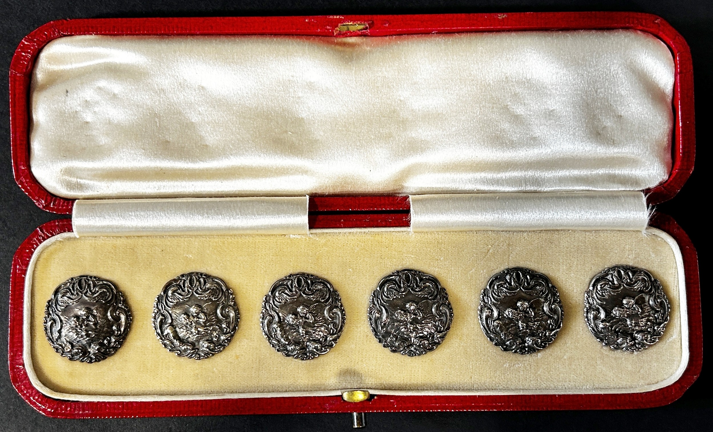 Six Levi & Salaman silver buttons of Cupid reviving Psyche all contained in a red Moroccan leather