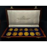 A wooden cased set of 12 Danbury Mint commemorative silver gilt oval medallions celebrating the