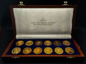 A wooden cased set of 12 Danbury Mint commemorative silver gilt oval medallions celebrating the